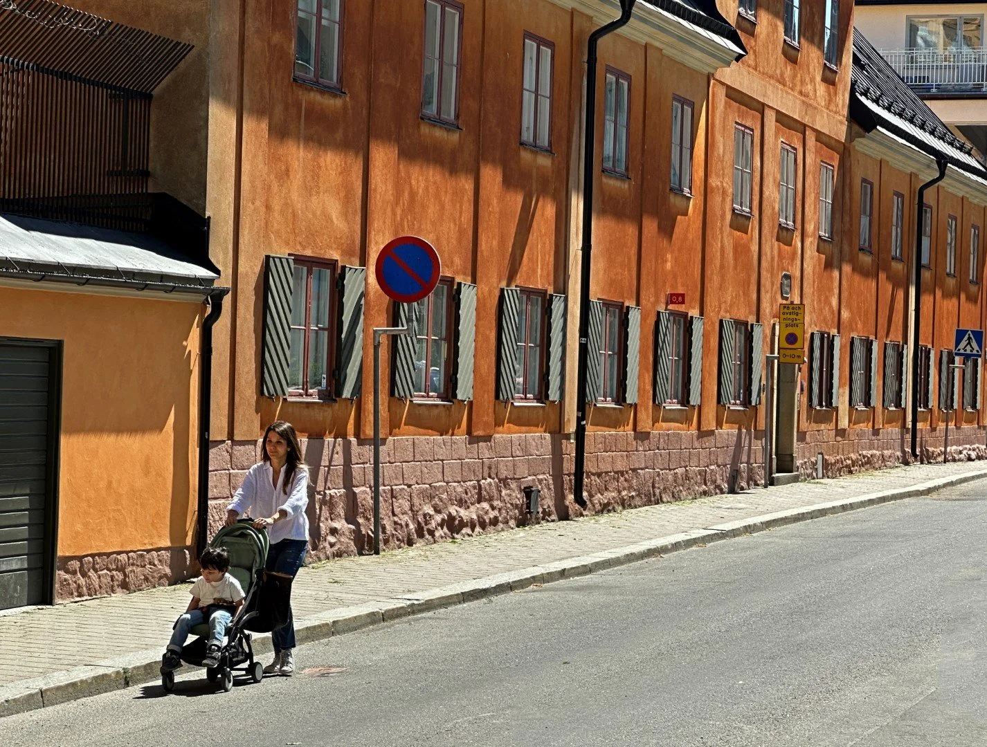 Woman pushes a stroller along Johannesgatan by the old grade school