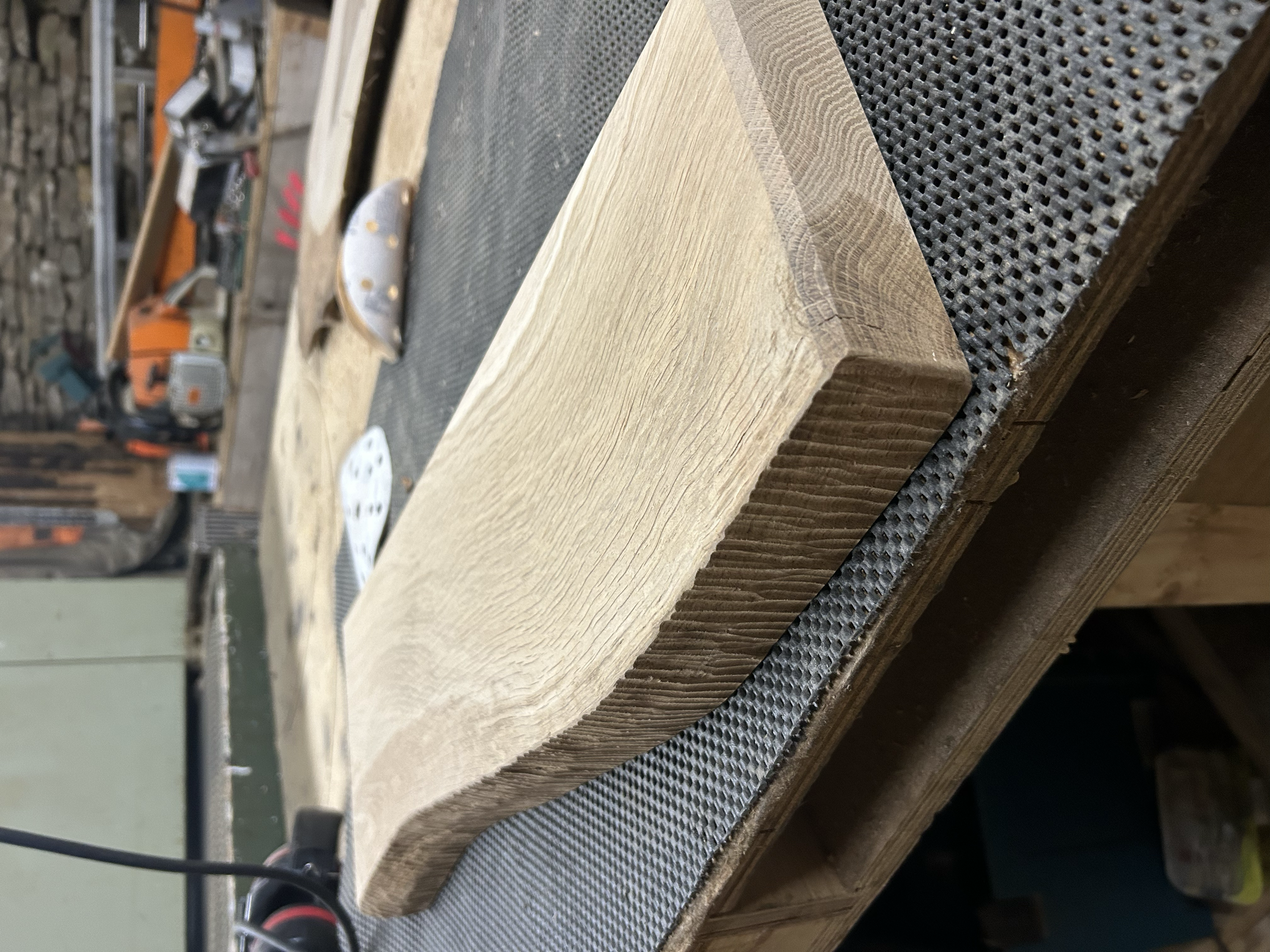 Close-up of a wooden piece with a carved groove on a workbench in a workshop.