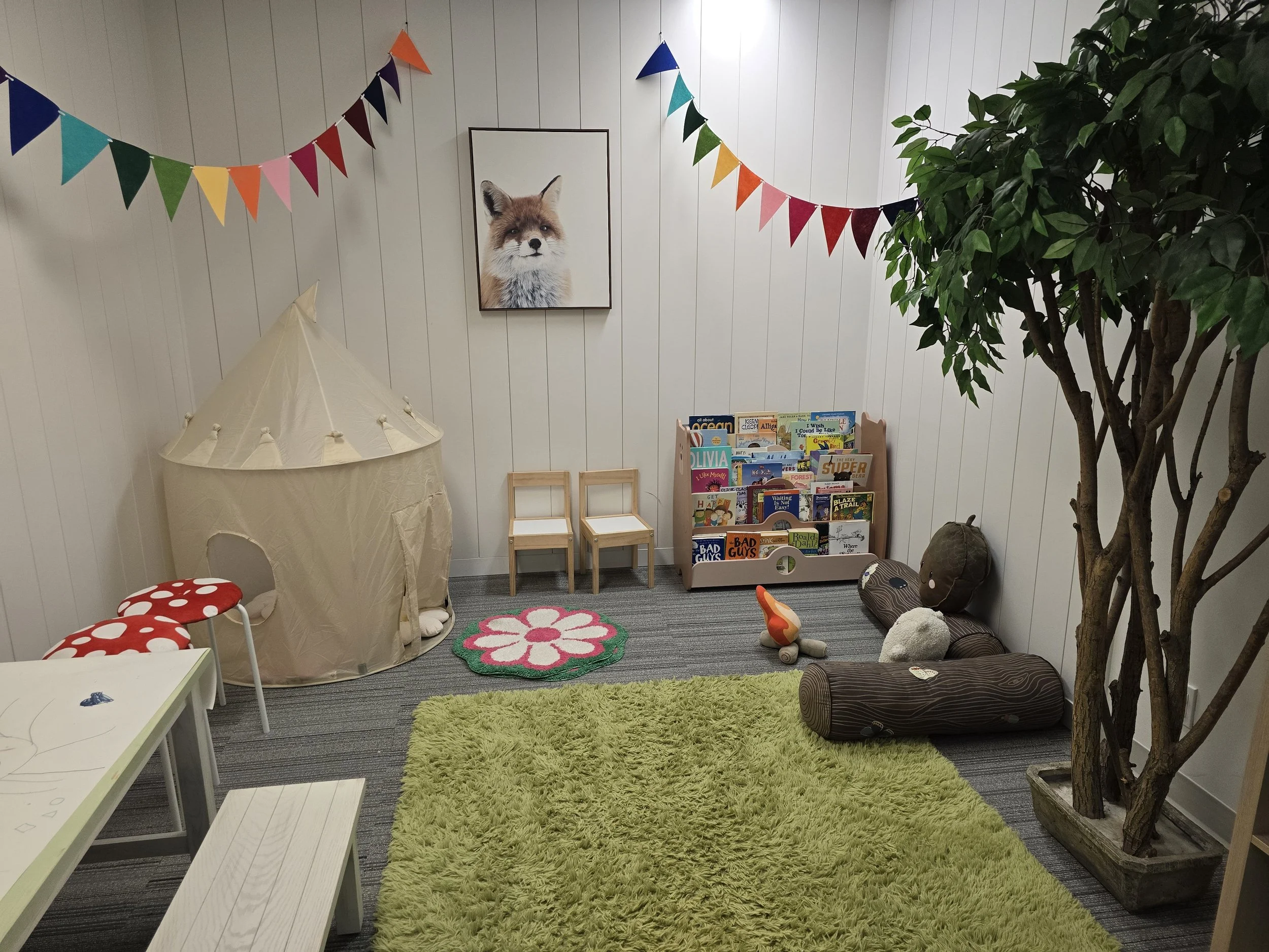 Playroom for children at Embark Psychology Calgary clinic with bright colours, fun atmosphere, colouring, books, play tent, and toys