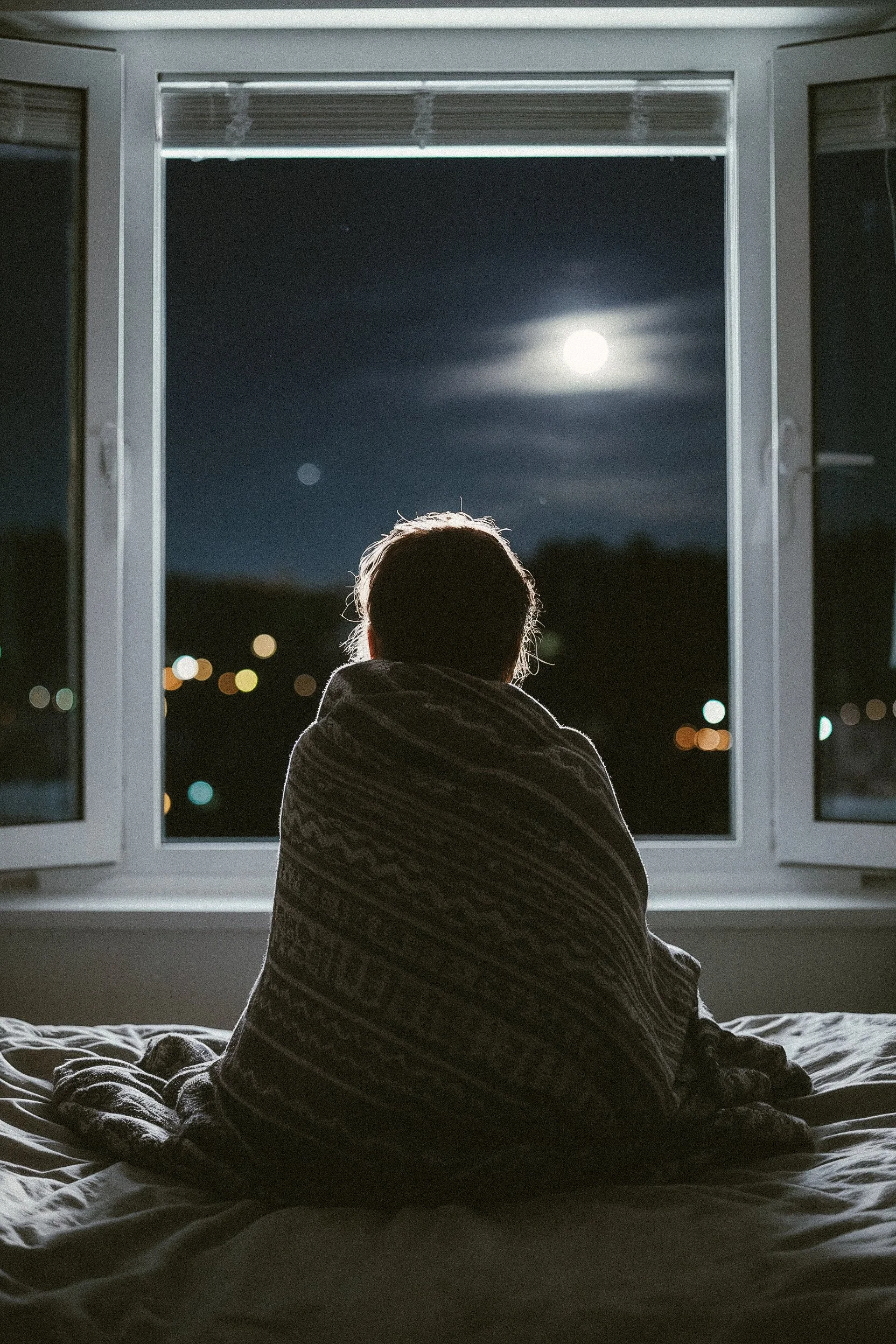 Woman looking out window at the full moon centering within