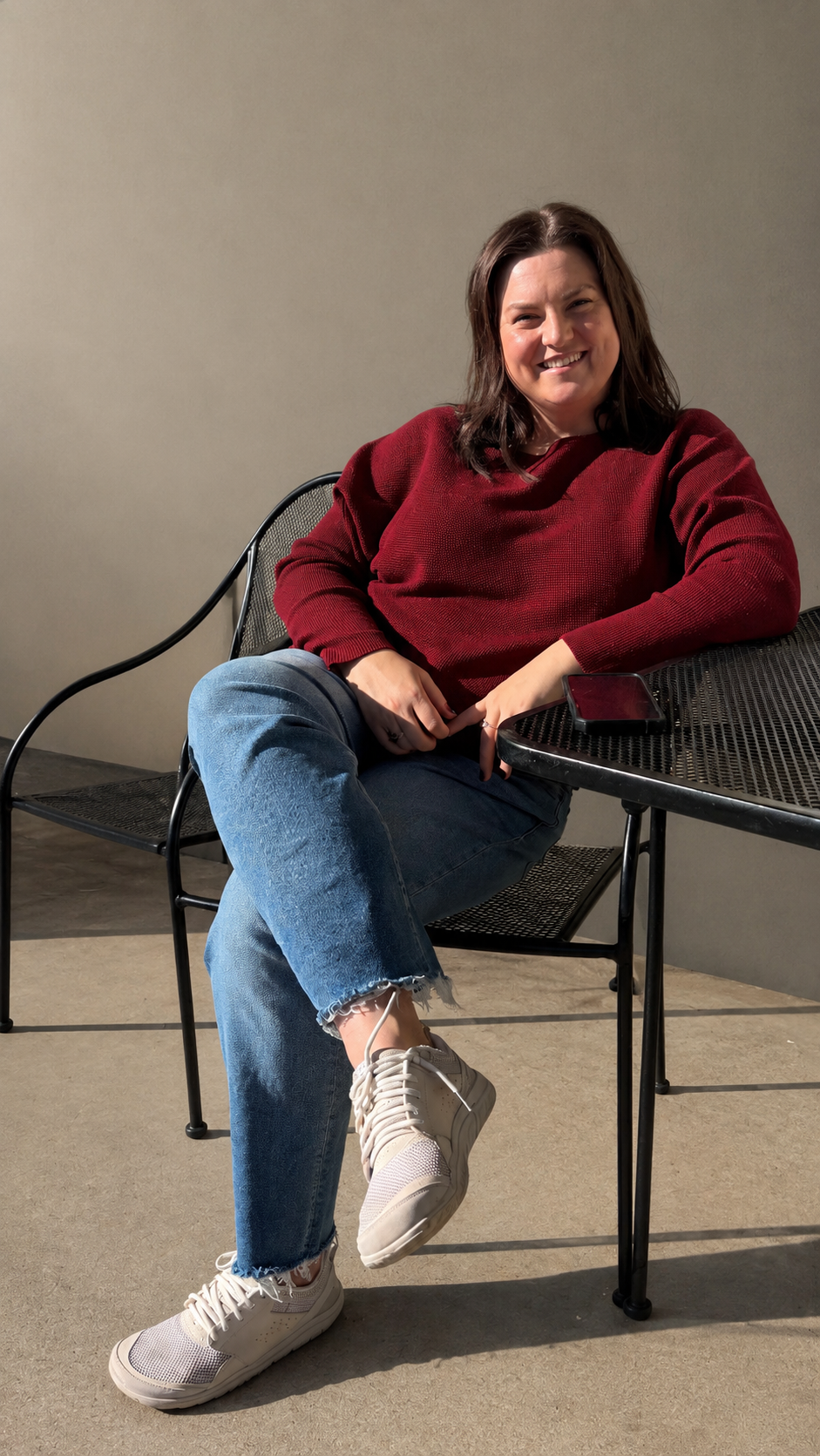 Sasha Krotova, LCSW smiling sitting in red sweater.