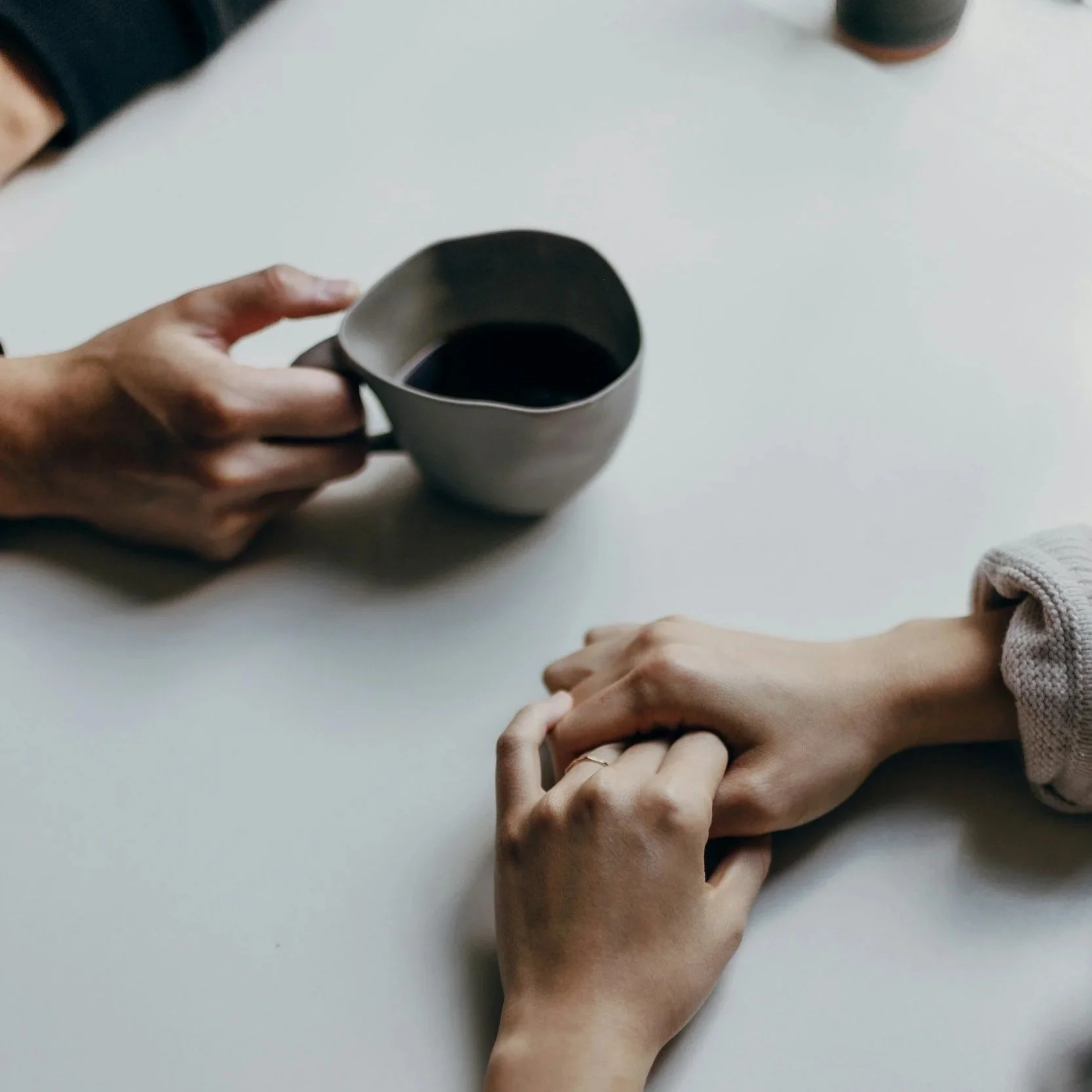 Silhouette of a person with long hair gesturing outdoors near a tree, with a blurred background.