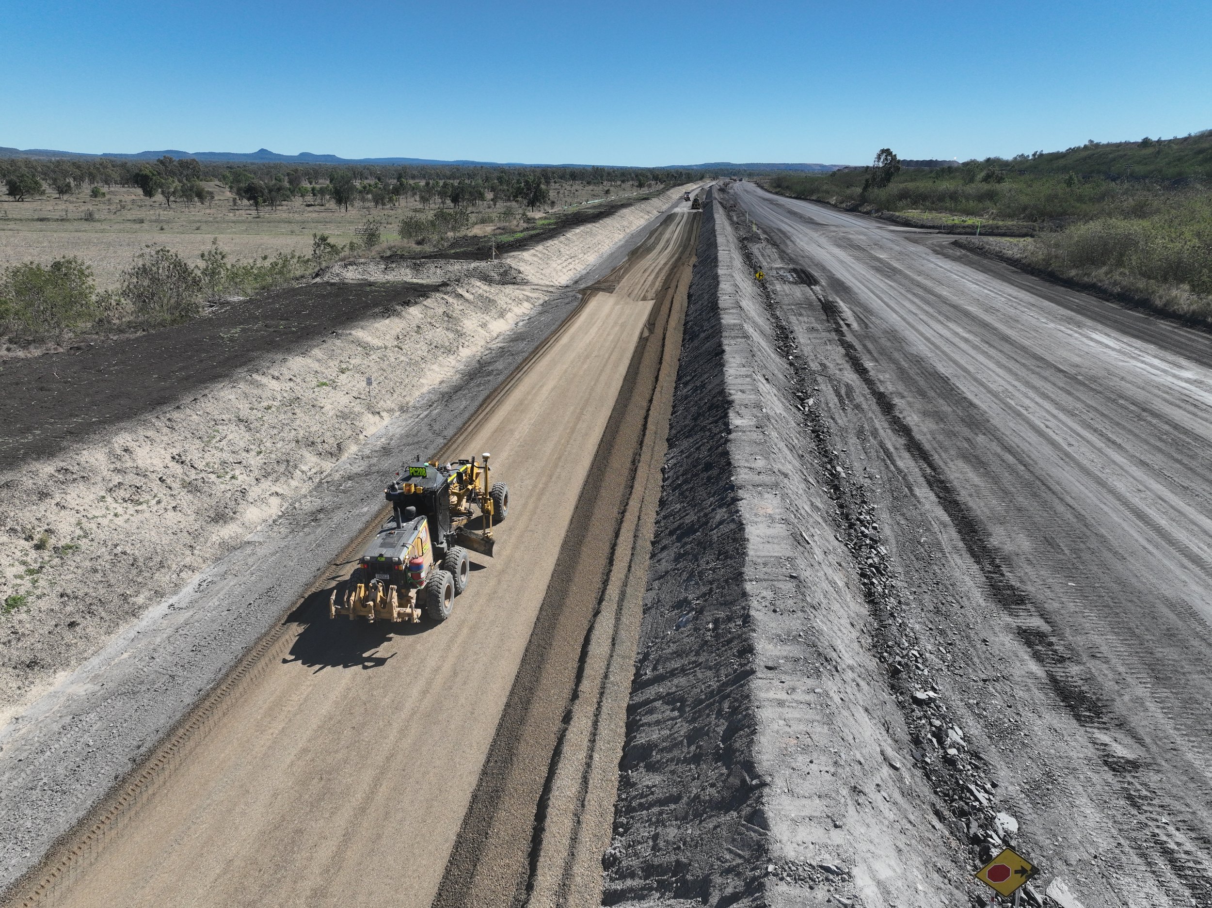 Mining machinery driving along haul road on regional mine site