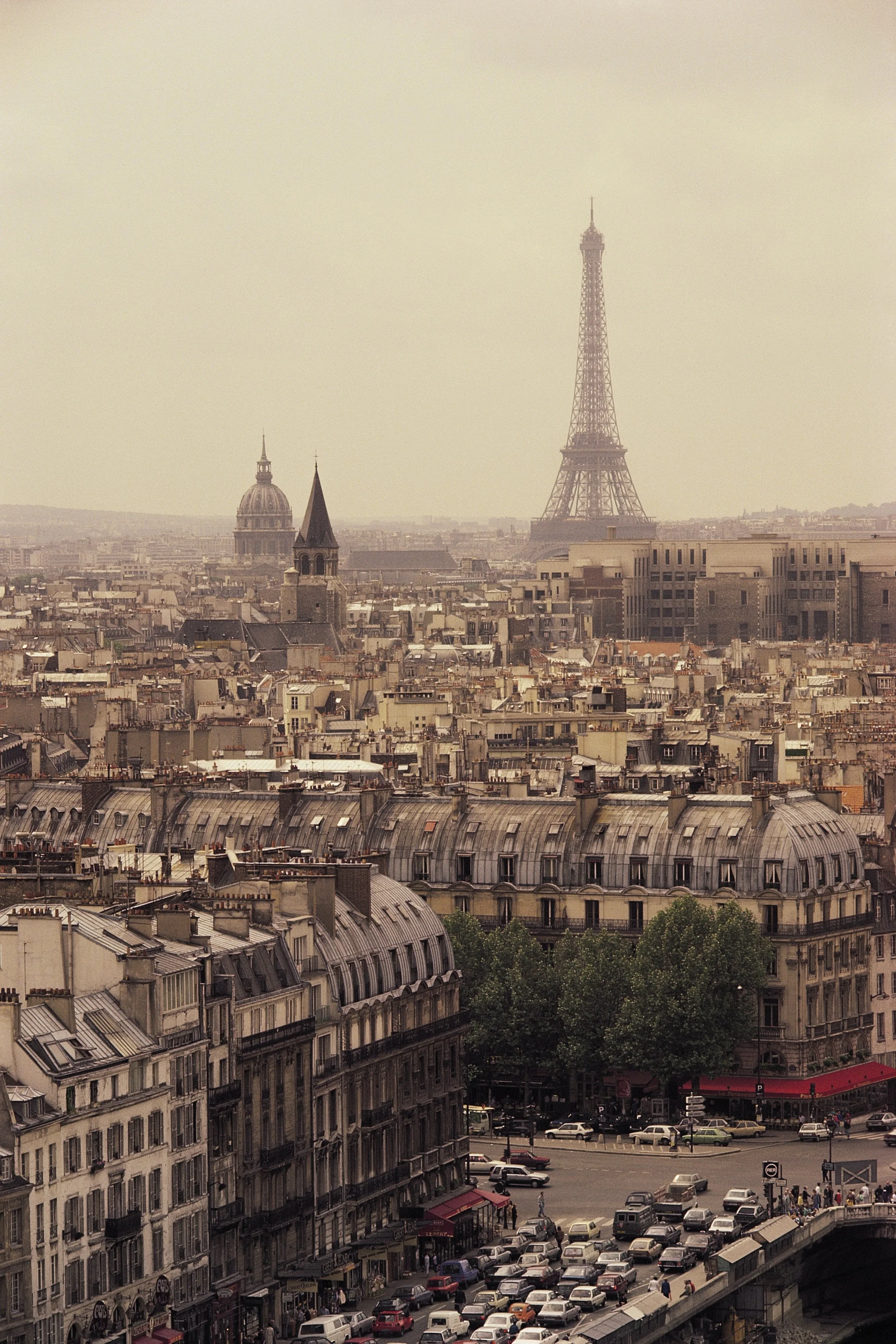 Cityscape view of Paris with Eiffel Tower in the background, classic Parisian rooftops, and early afternoon traffic.