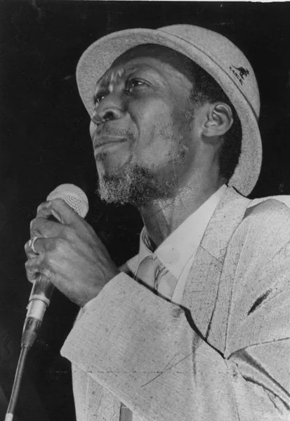 Black-and-white portrait of Alton Ellis performing on stage.