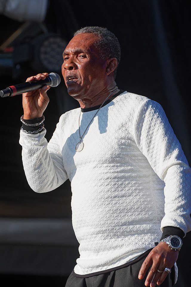 Colour portrait of Ken Boothe holding a microphone, capturing the legendary Jamaican singer known for his soulful reggae & rocksteady hits.