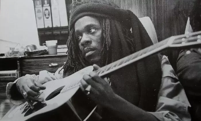 Black-and-white image of Dennis Brown playing the guitar/