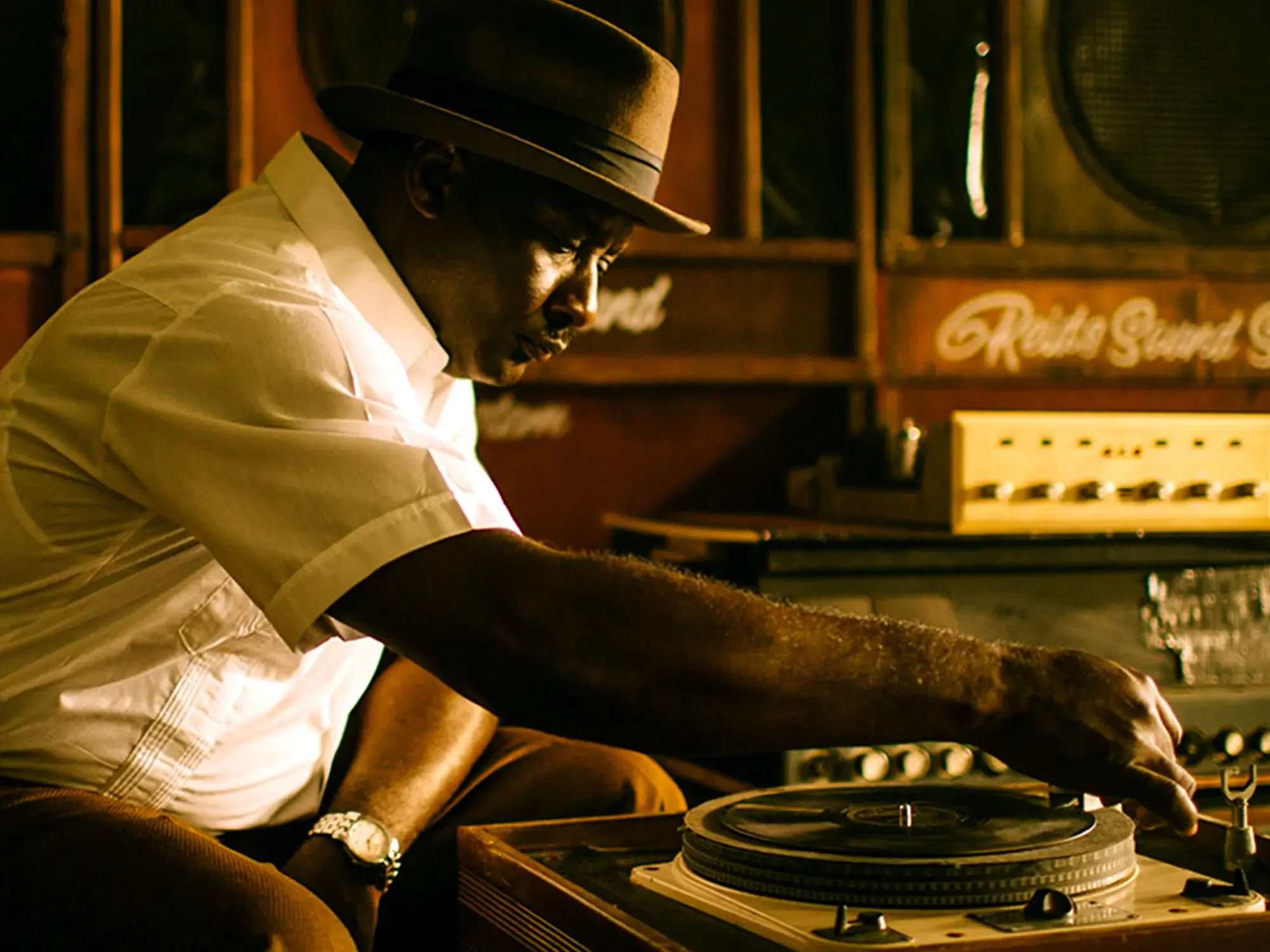 "Actor portraying Duke Reid sitting in a studio for the documentary 'The Story of Trojan Records'."