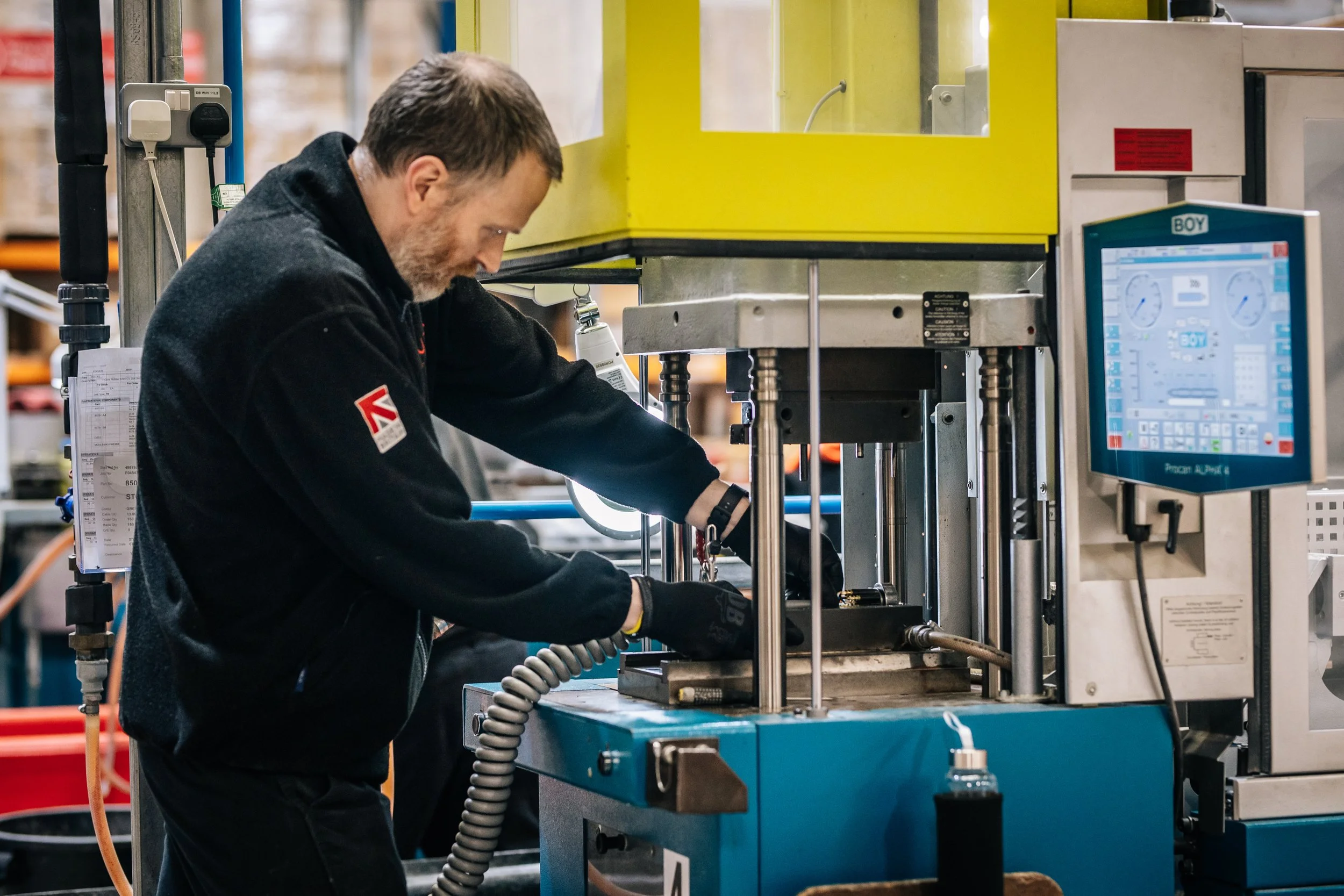 Worker operating a hydraulic press machine in an industrial workshop.