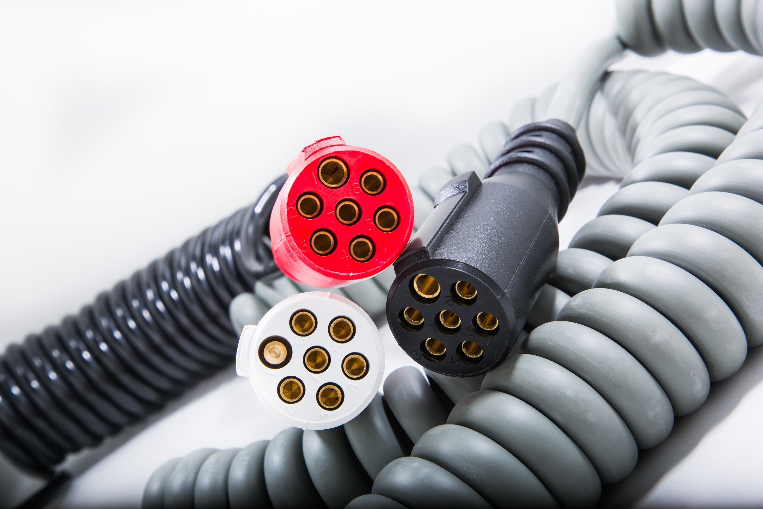 Electrical cords with different colored connectors, including red, white, and black, against a white background.