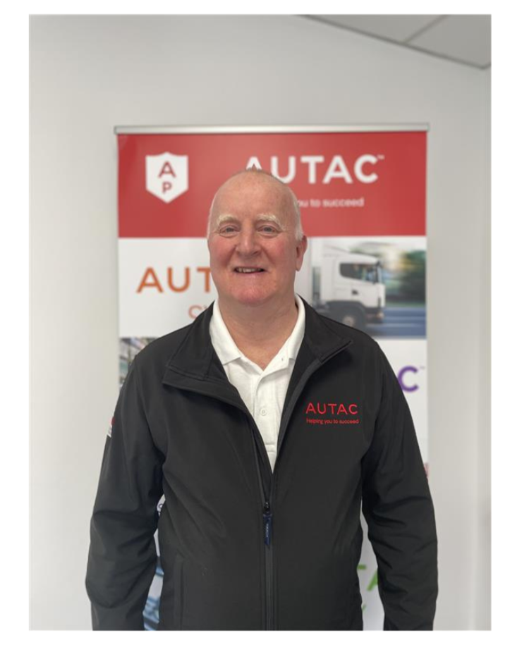 Image of Simon Pearce, Technical Director, stood in front of Autac banner wearing black jacket with Autac logo. 