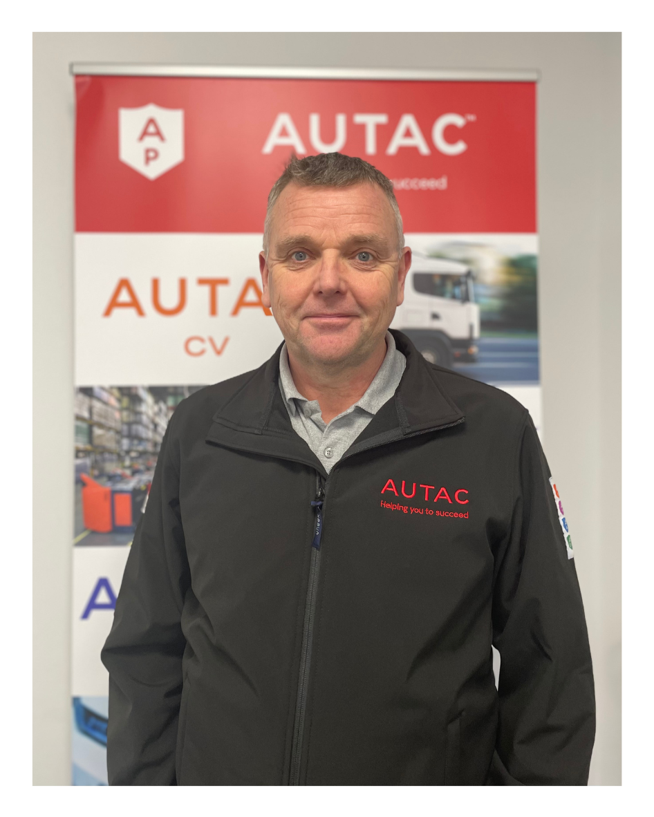 Image of David Lowe, Managing Director,  stood in front of Autac banner wearing black fleece with Autac logo. 