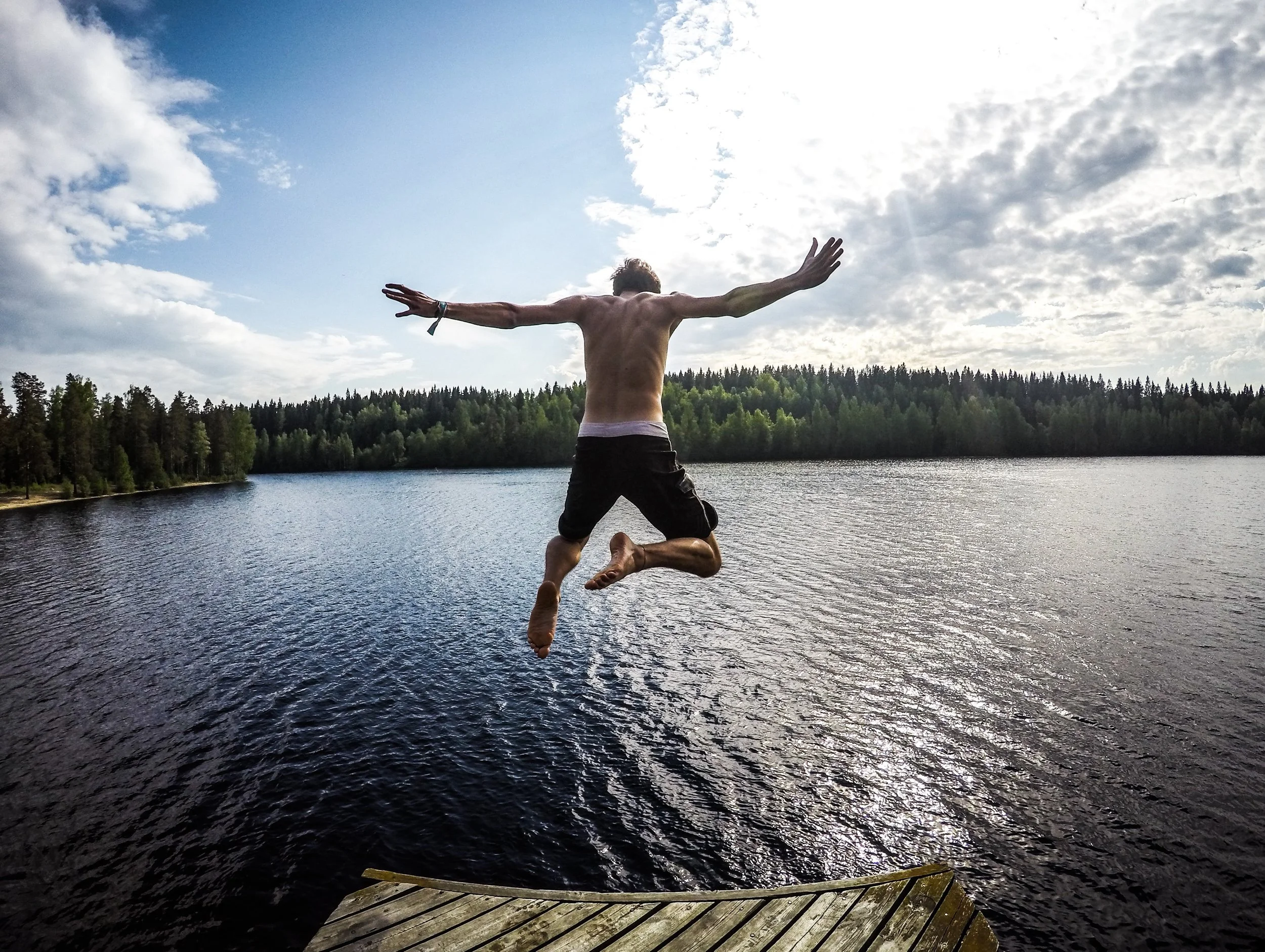 young man jumping into lake