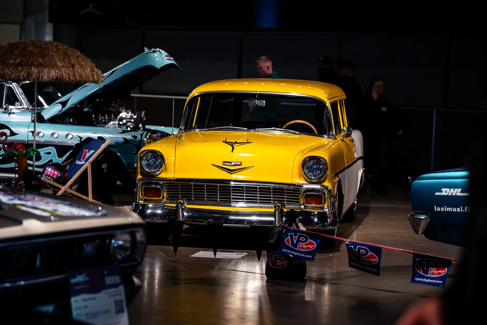 Keltainen classic-autokuva autonäyttelyssä, ympärillä muita vintage-autoja ja ihmisiä.