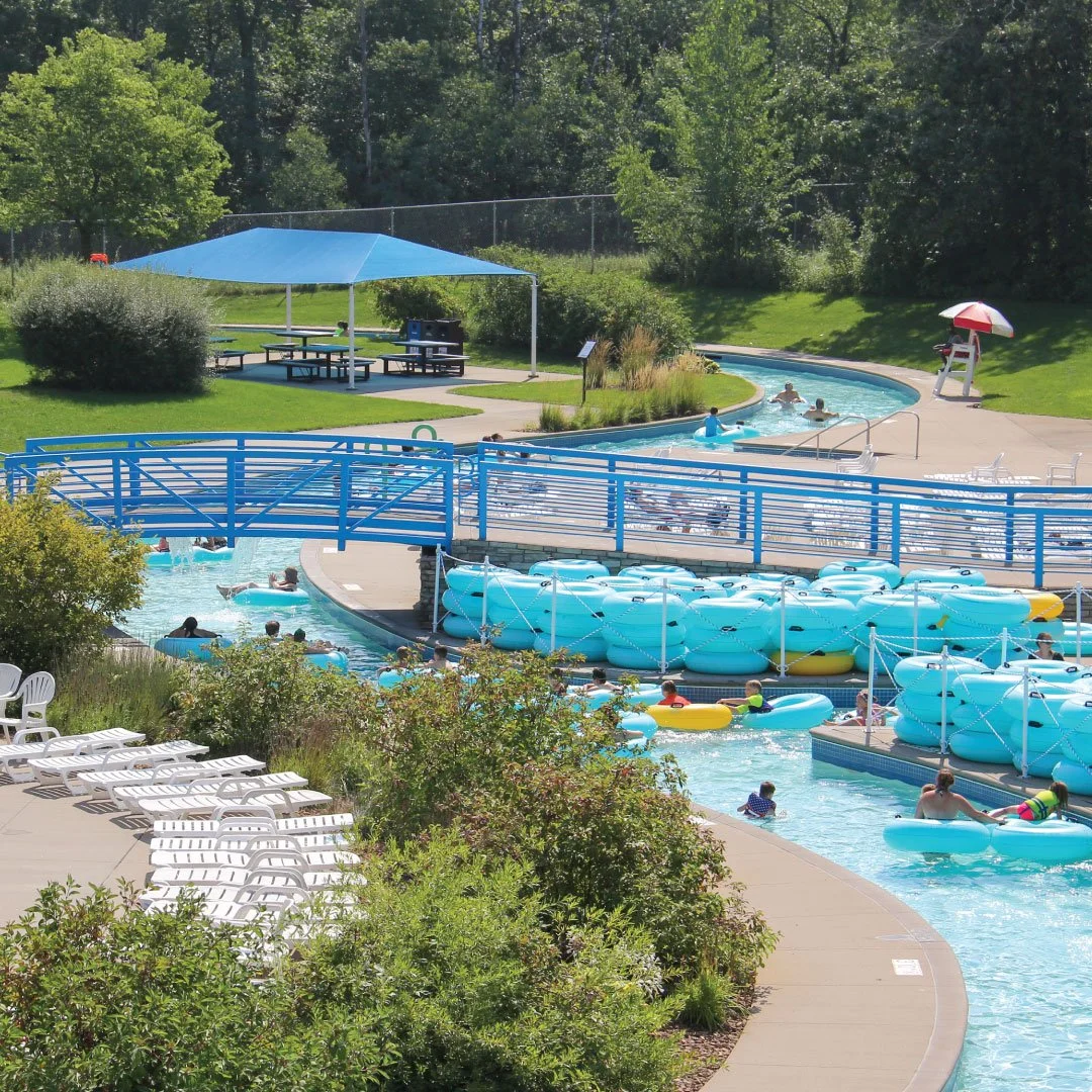 The lazy river around Bunker Beach Water Park has a blue bridge that crosses over into the middle where another pool and cabanas are located.