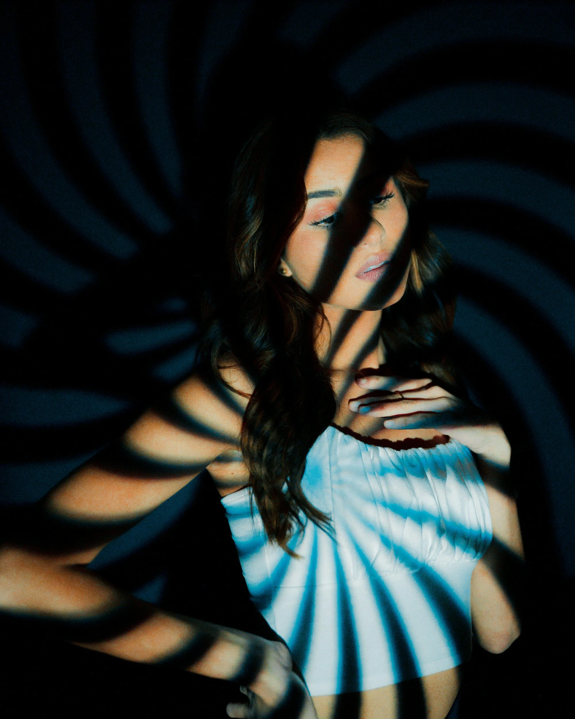 Une femme aux cheveux bruns portant une robe blanche est partiellement visible, avec des rayures noires semblant entourer l'image.