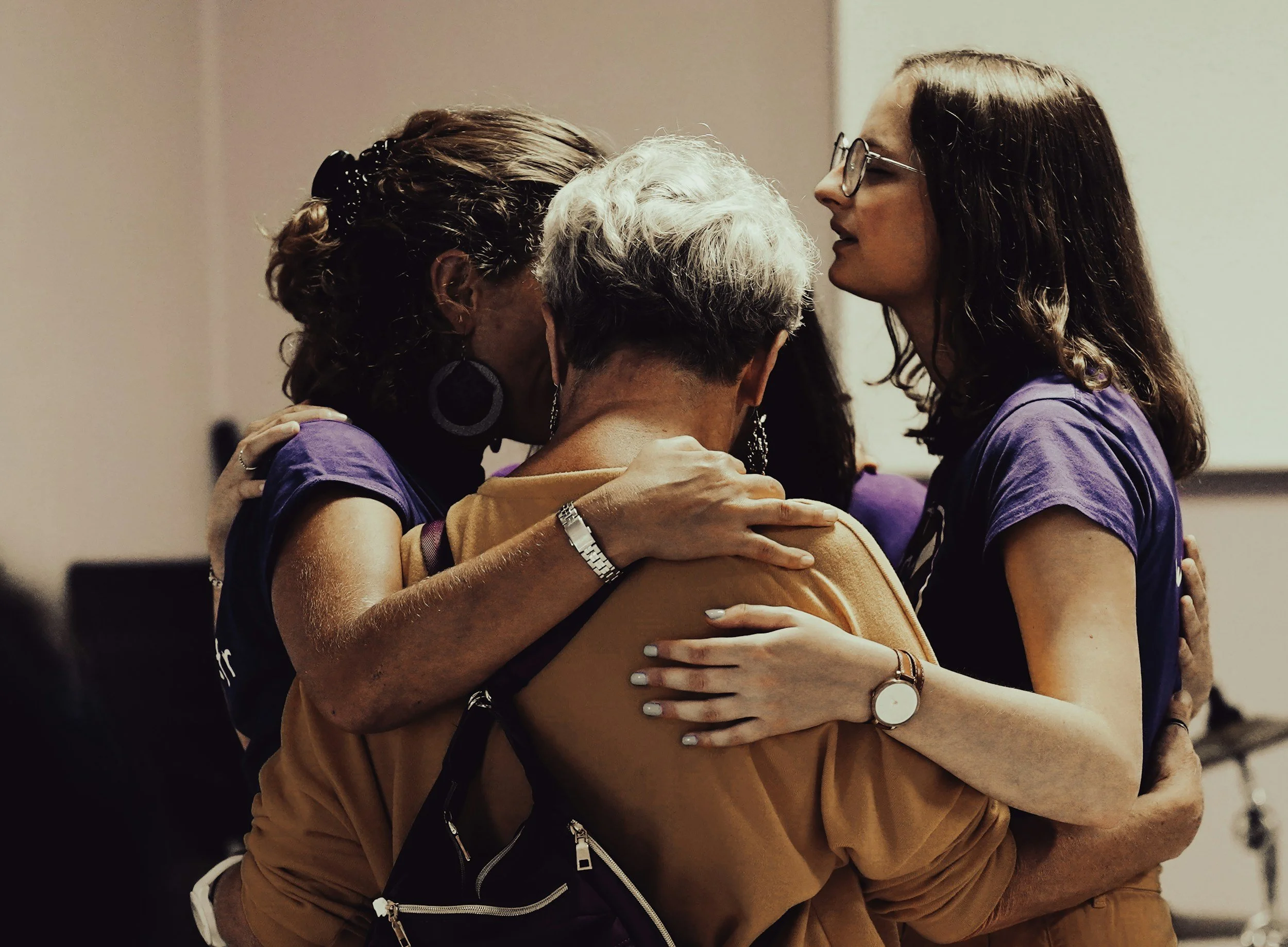 Quatre personnes s'embrassent lors d'une poignée de main chaleureuse, manifestant de l'affection et de la solidarité.