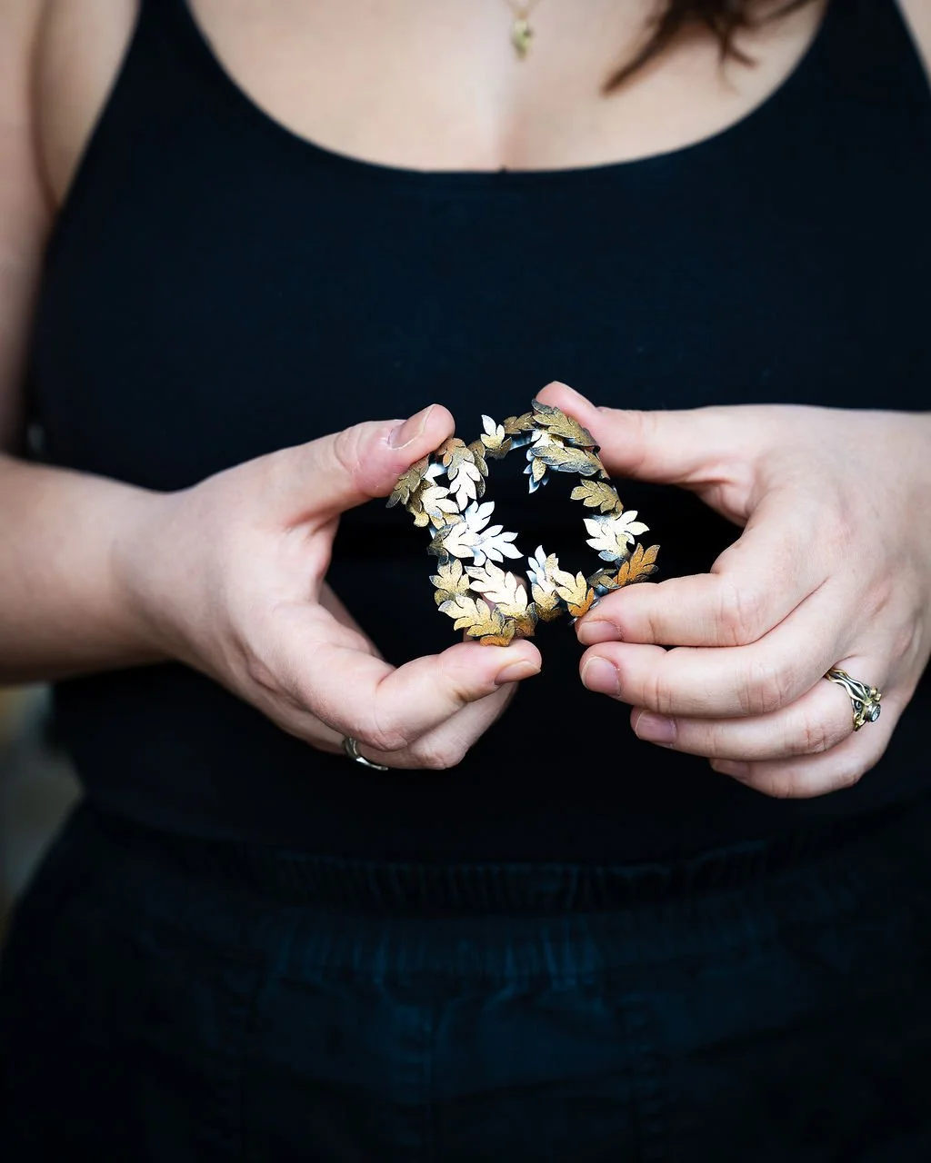 Holding a hand-pierced acanthus necklace in oxidised silver and 24ct gold