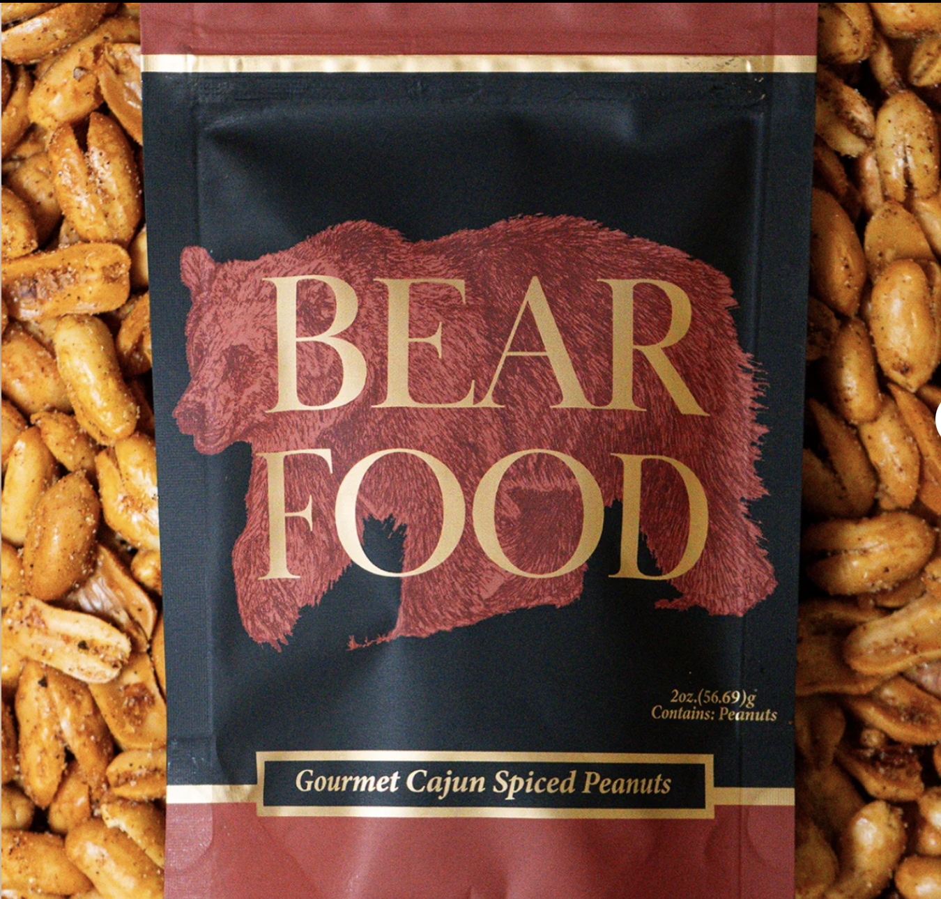 A package of Bear Food Gourmet Cajun Spiced Peanuts with a red bear silhouette in the center of the packaging. The package contains 2 ounces (56.69 grams) of peanuts, which contain peanuts.