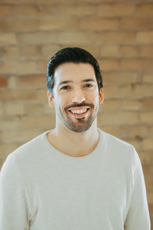 Javier Osuna Siles, smiling, with a beard and a white sweater.