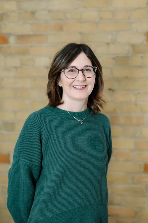 Jenny Skluzacek, wearing glasses and a green sweater.