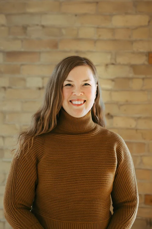 Halen Bower, with long wavy brown hair and a brown turtleneck sweater.