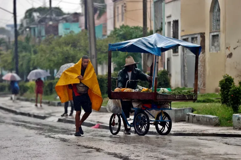 People shelter from the rain in Santiago de Cuba, southern Cuba, October 28, 2025 [Ernesto Mastrascusa/EPA]