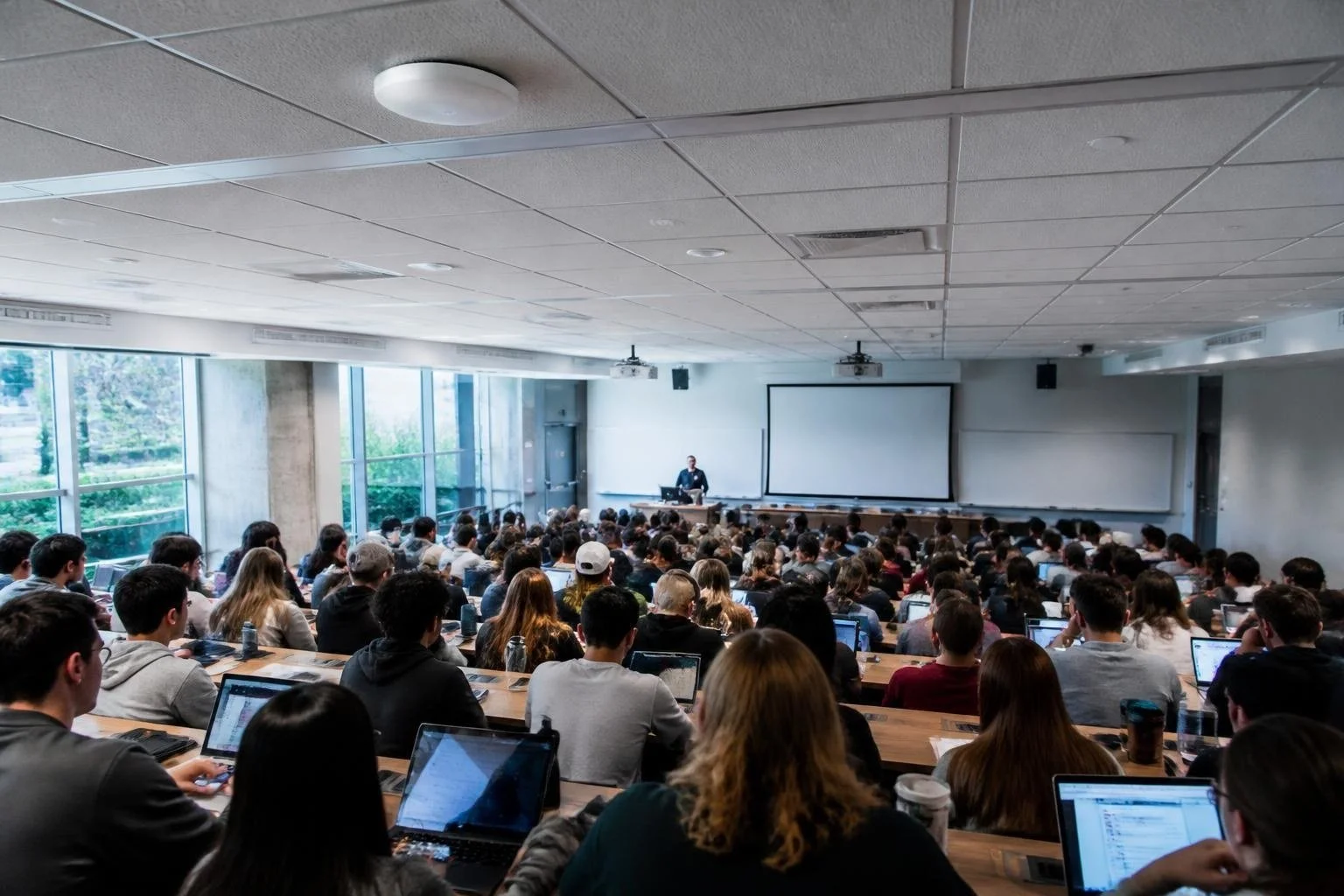 Ceiling wireless access point above a full university lecture hall with students using laptops and phones