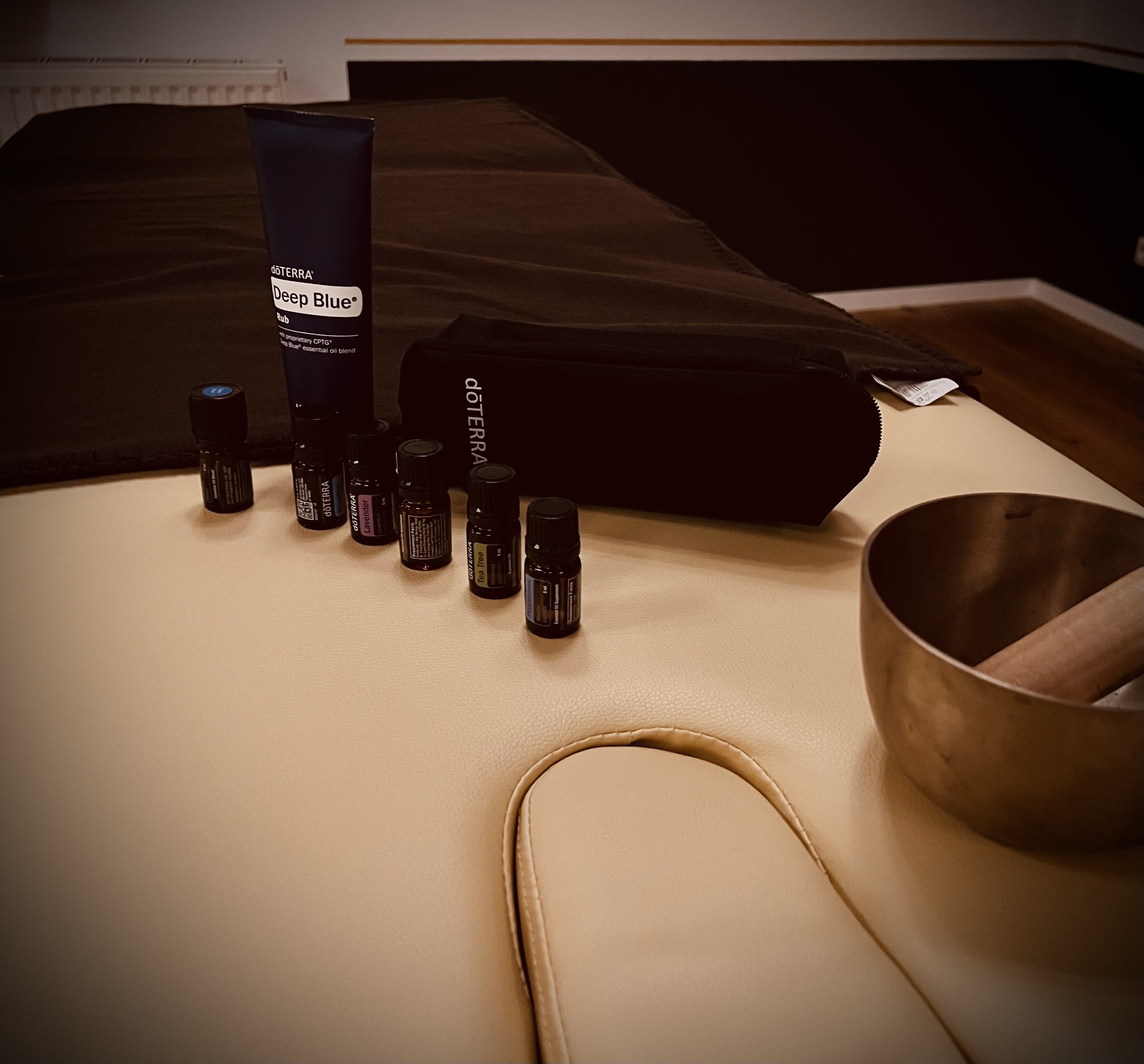 Verschiedene ätherische Öle auf einem Tisch neben einer schwarzen Tasche und einem Meditationskissen.