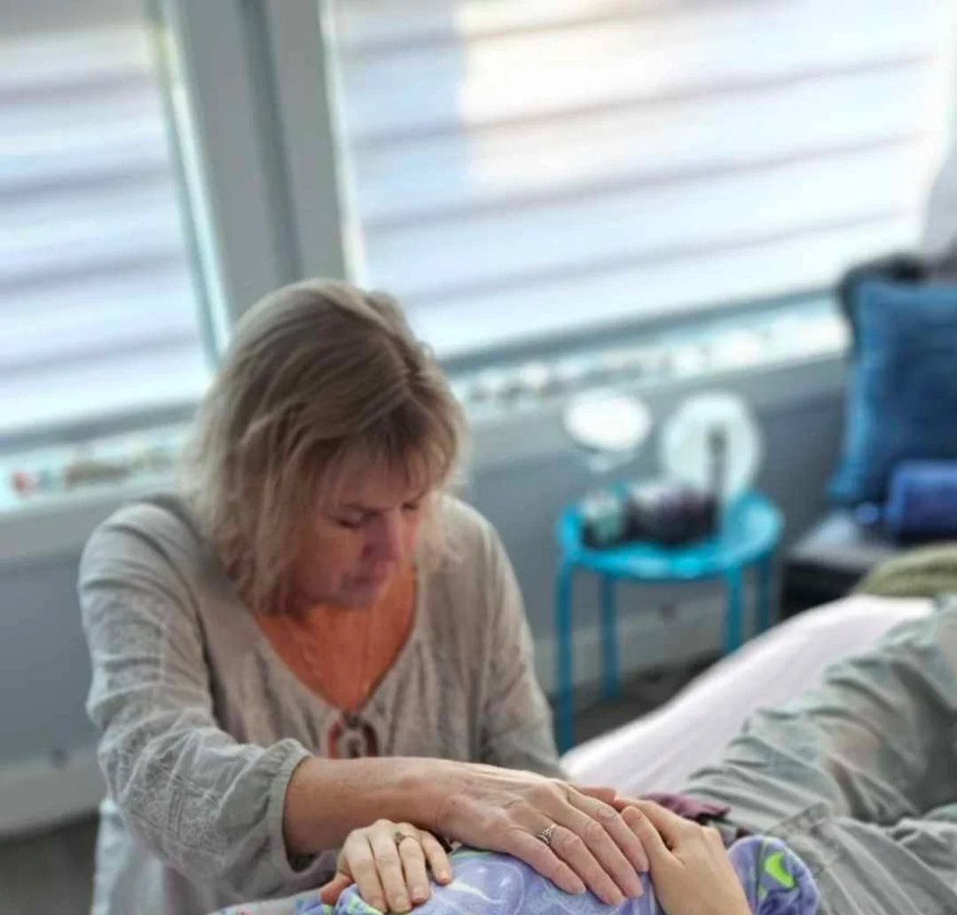 A woman lying on a hospital bed with a concerned expression, holding and comforting a young child lying beside her.