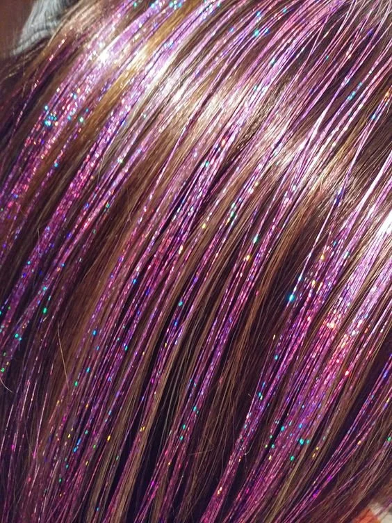 Close-up of hair with pink, purple, and blonde streaks and glittery highlights.
