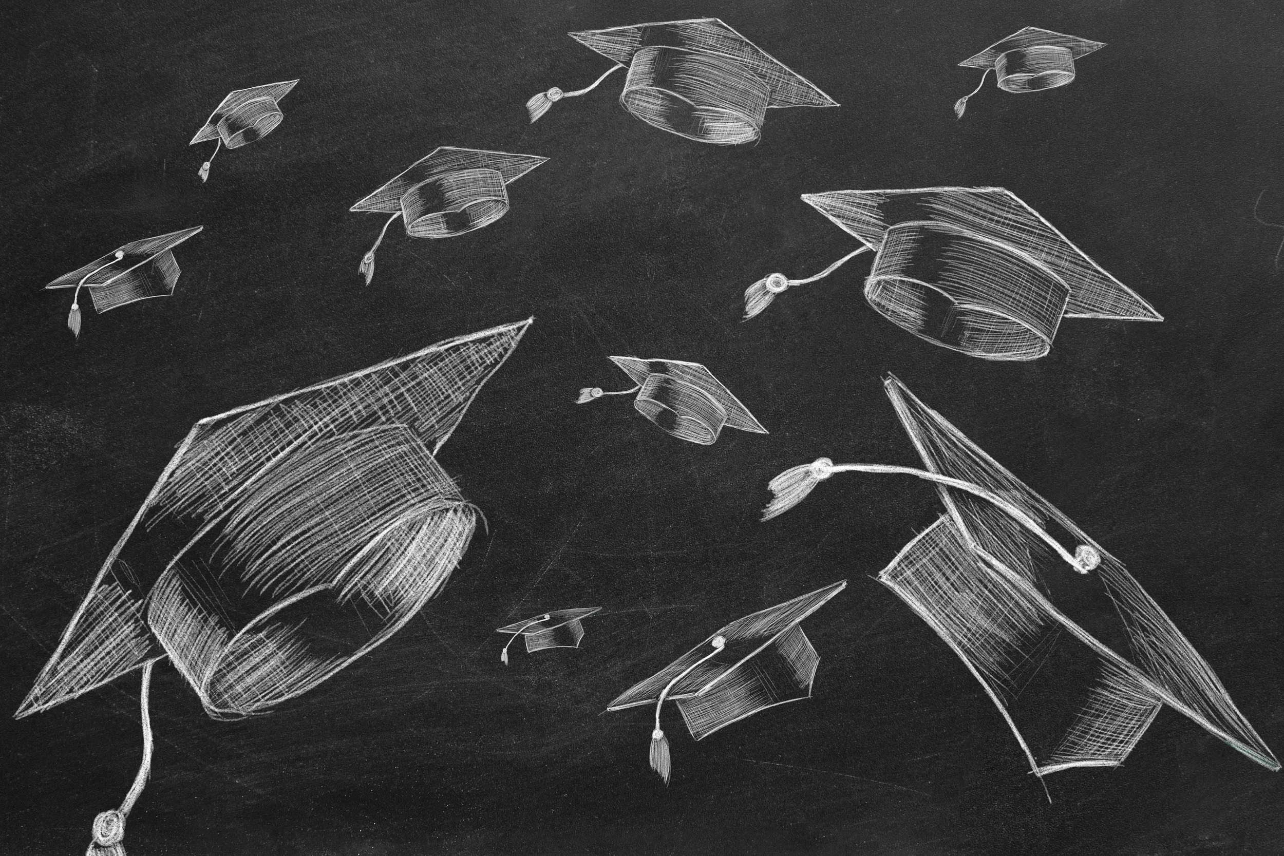 Chalk drawings of graduation caps floating in the air on a blackboard.