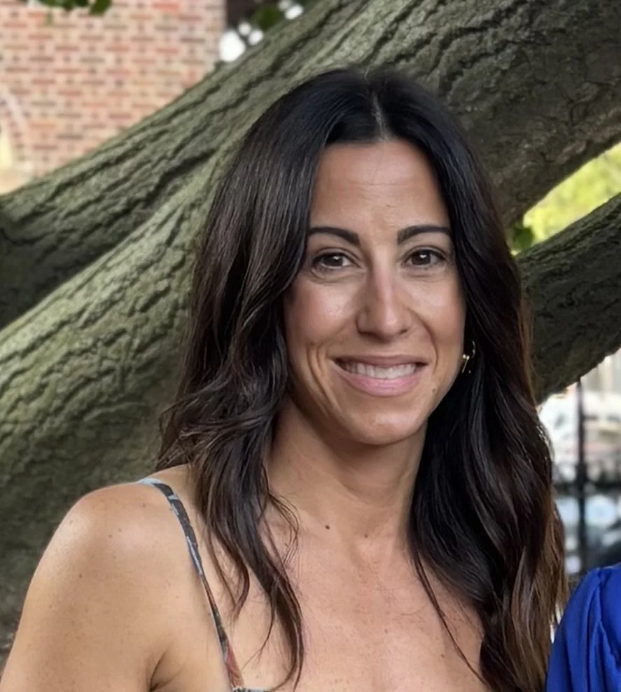 A woman with way brown hair smiling while looking at the camera