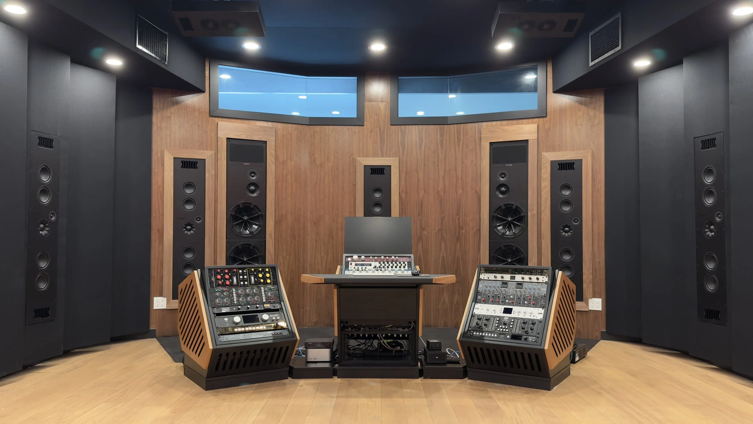 Recording studio with large speakers, audio equipment, and wooden panels