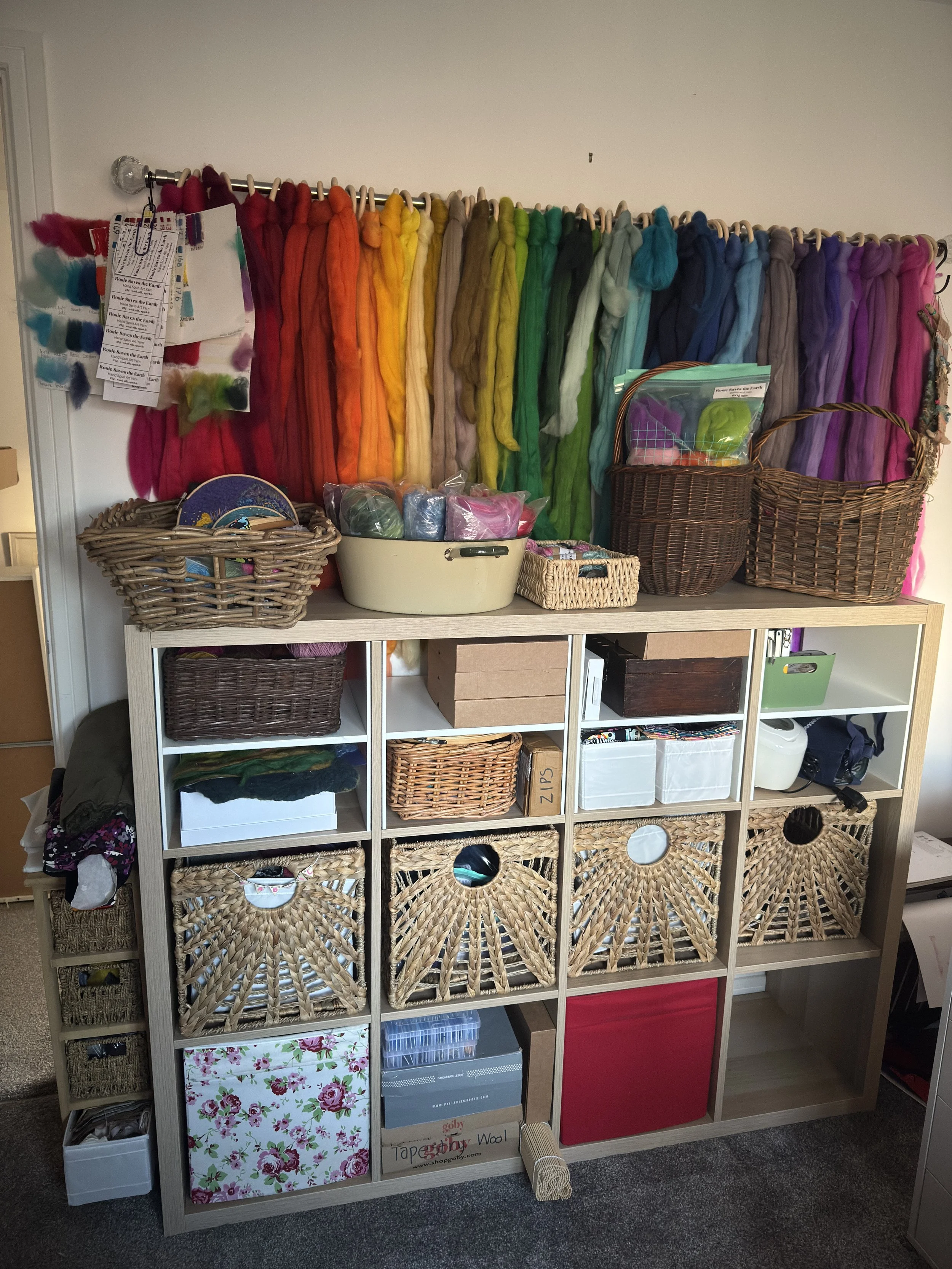Craft room with colourful wool rovings hanging on a wall, and cube storage filled with baskets and supplies
