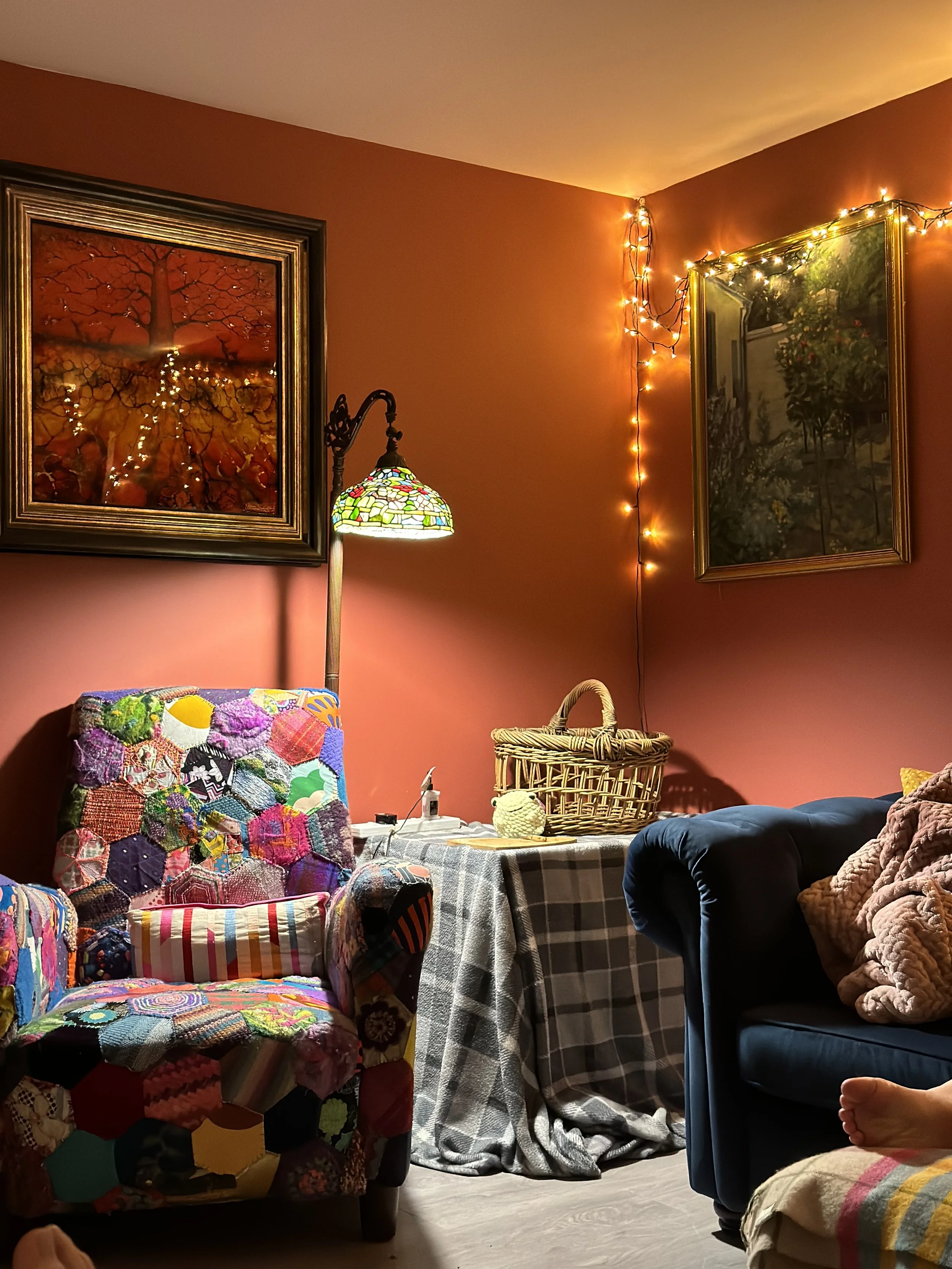 Cosy living room corner with red walls, an armchair, and fairy lights