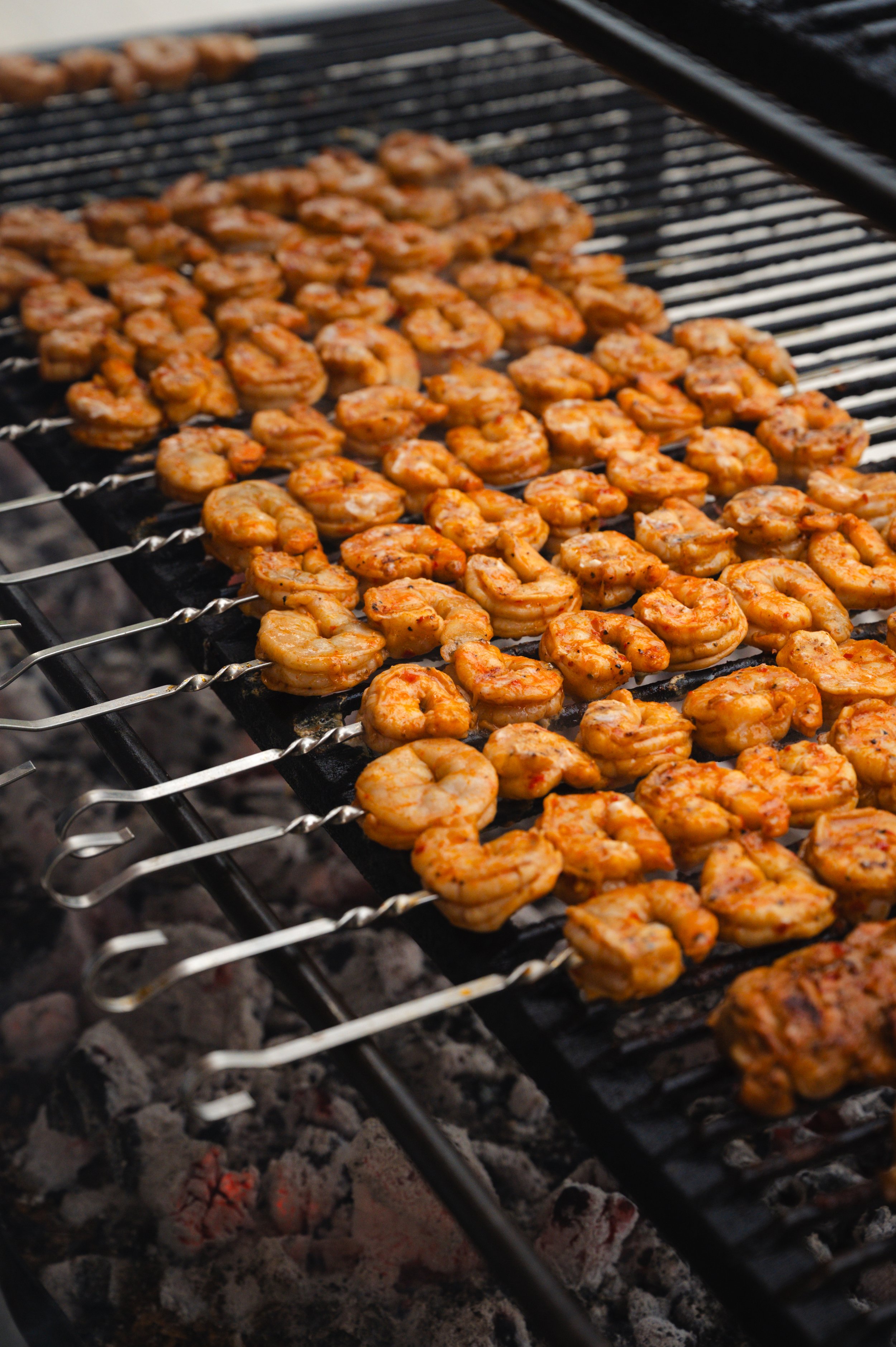 Shrimp skewers cooking on a grill over hot coals.