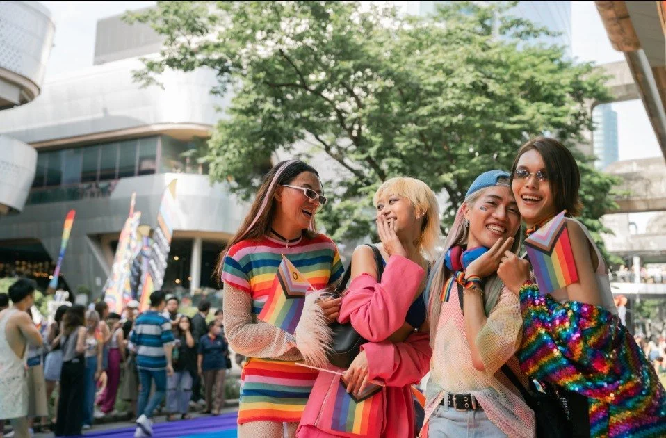 four girls laughing, wearing rainbow outfits