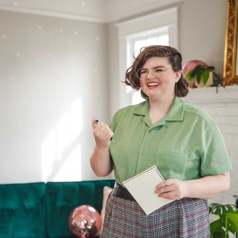 Queer Therapist, Non binary, taking notes and smiling