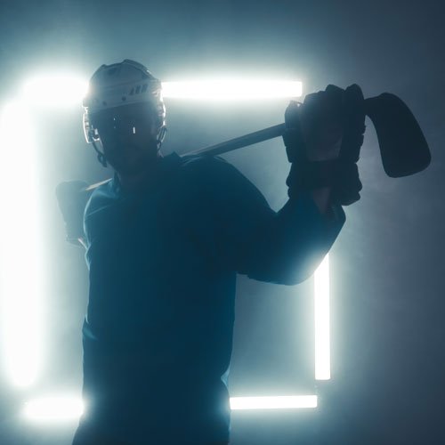 Sexy Hockey Player holding stick in front of neon square lights