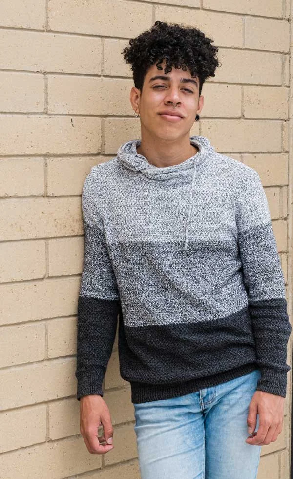Young man with curly black hair looking confidently at the camera