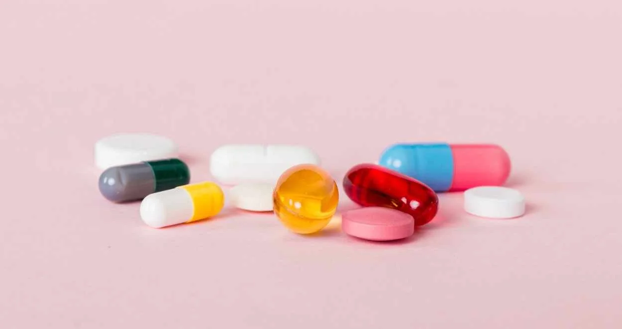 Pink, blue, trans colors, white, yellow, gray pills on a light pink background