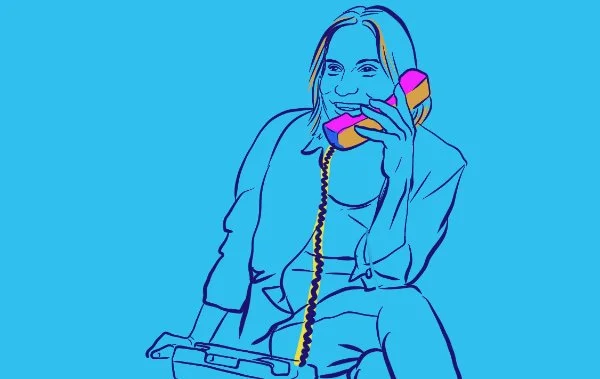a woman smiling, talking on a landline phone