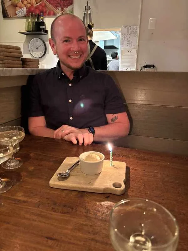 Eben with a giant smile in front of a scoop of ice cream and a candle