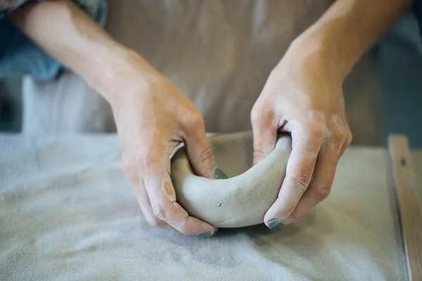 Hands building a pot out of clay