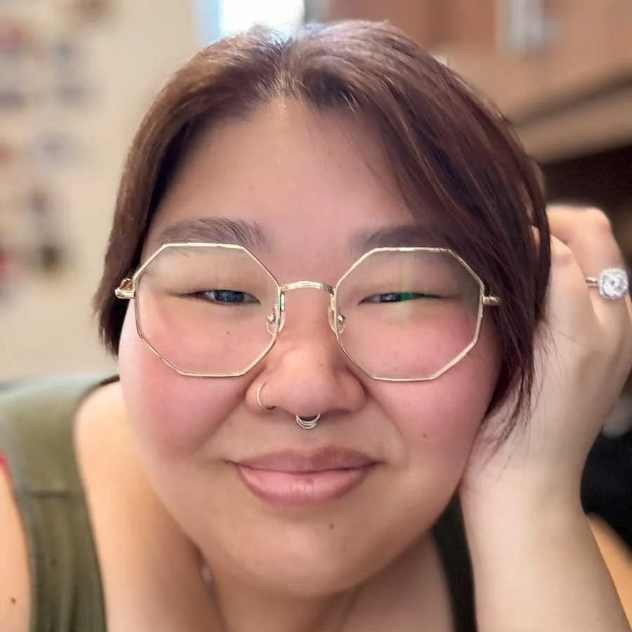 Close up portrait of Carly wearing modern hexagonal glasses and smiling