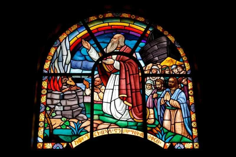 Image of stained glass in a church with a saint and a rainbow