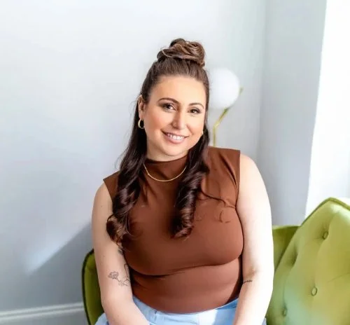 Lauren Levy smiling and sitting on a green velvet couch