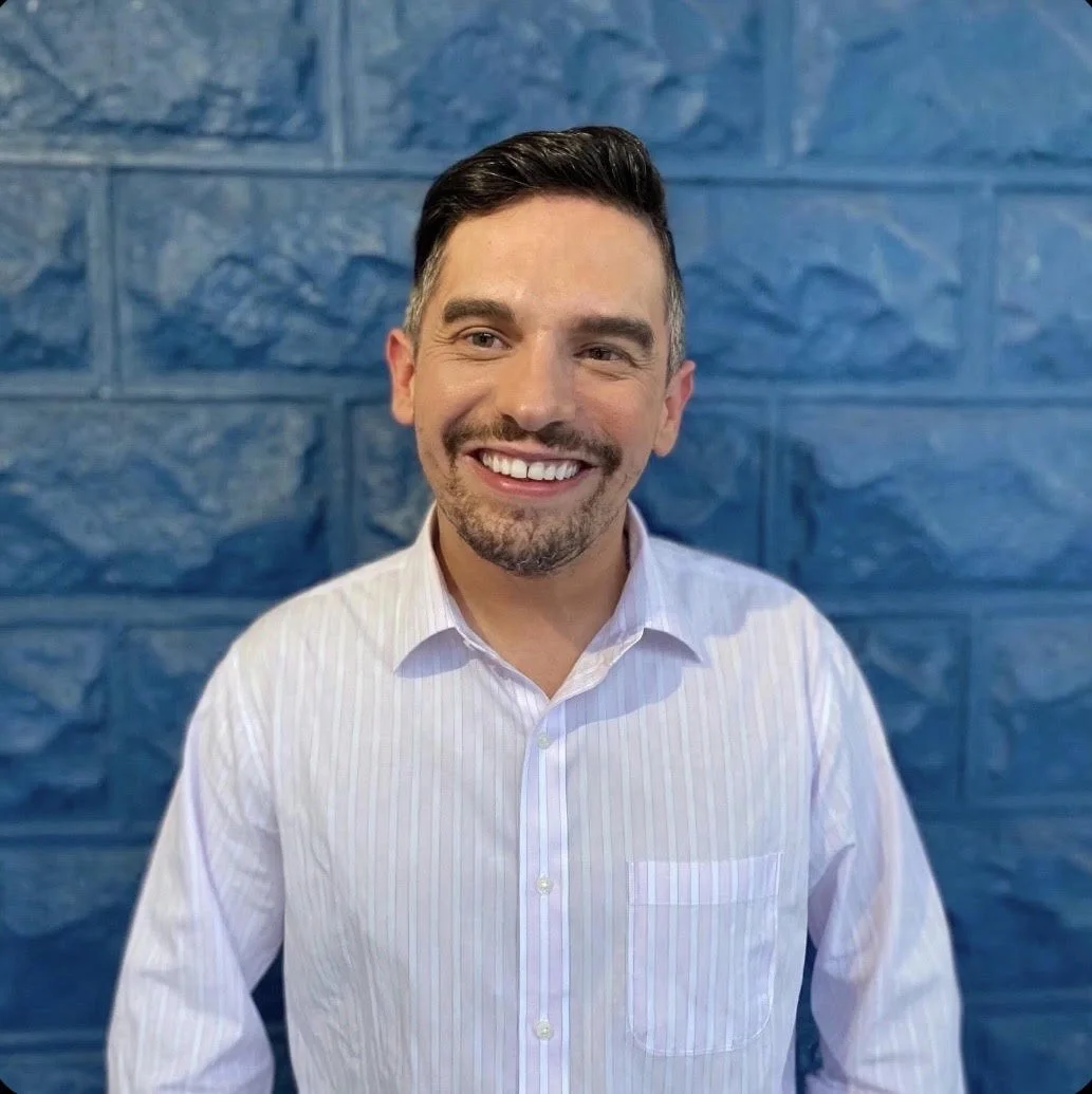 A headshot of Sean wearing a white button down shirt