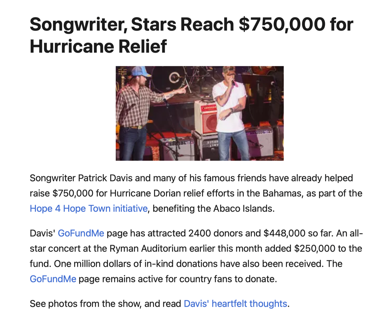 Patrick Davis speaking into a microphone on stage with another person playing guitar behind him during a concert.